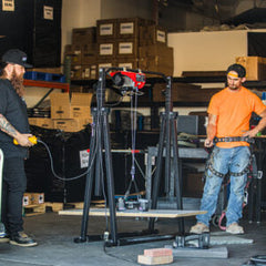 GRABO GR-V1 wireless remote demonstrated by two operators beside a workshop hoist. Application photo; hoist and lifters not included.